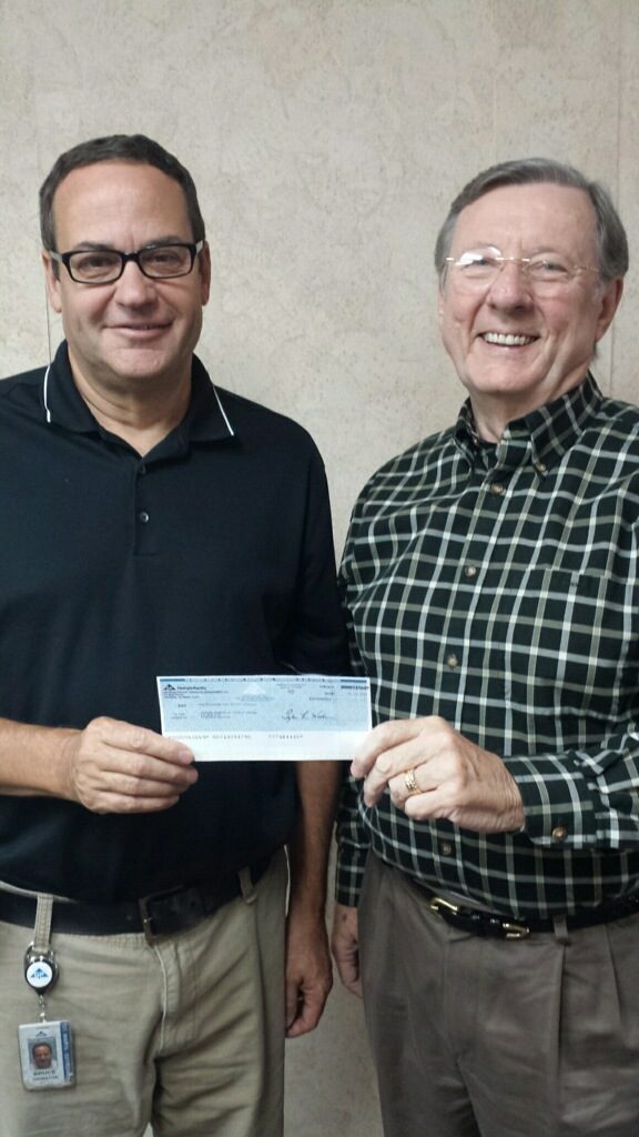 Georgia Pacific's Bruce Ormiston presents Ken Boden a check for $1,000 to support Camden House.